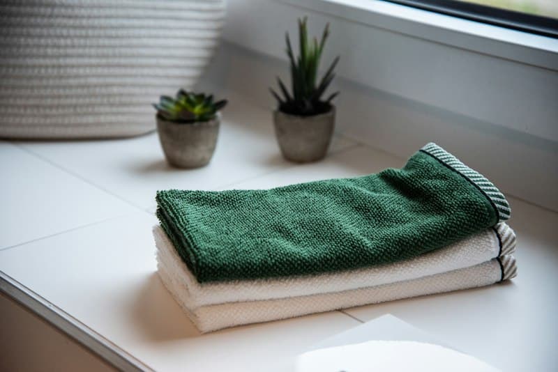 Freshly folded towels stacked beside potted plants on a clean windowsill