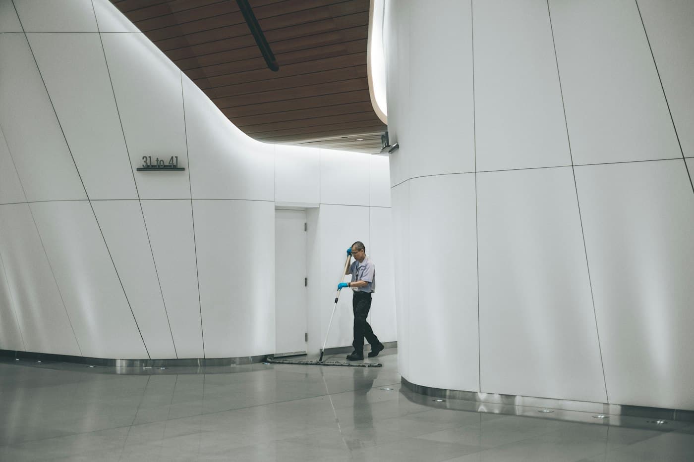 A cleaner working across the floor of a large white commercial building