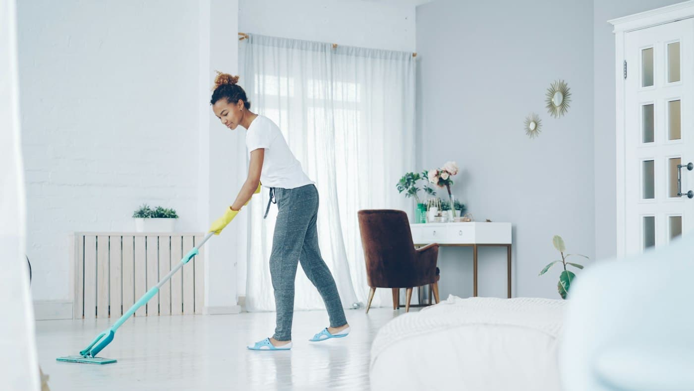 A cleaner mopping the floor of a bright, modern living room